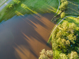 Playing field flooded with dirty brown floodwaters after heavy rain
