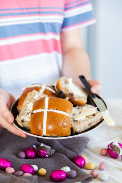 Buttered hot cross buns and scattered eggs at Easter on a plate