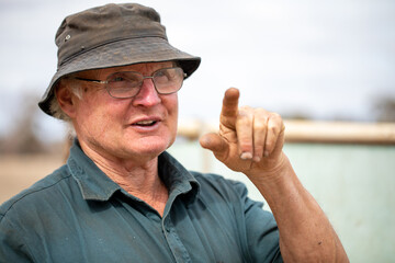 head and shoulders of older manual worker pointing index finger