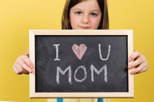 I love you mom message written on blackboard by little girl. Mother's day concept.