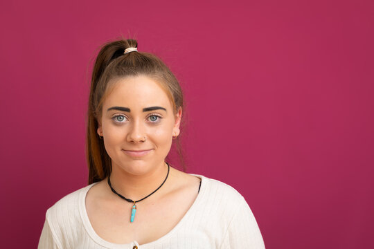 Head And Shoulders Of Young Woman With High Pony Tail On Pink Background