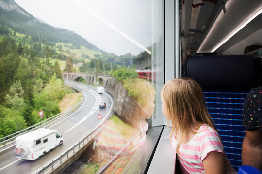 Girl looking out window at highway on train