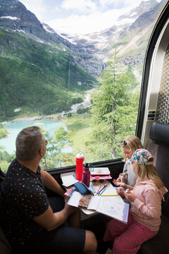 Family sitting on train by mountains