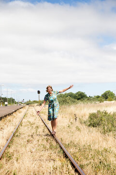 Smiling woman balancing on train tracks