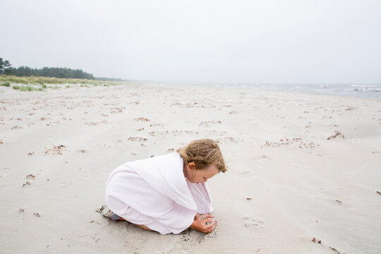 Girl wrapped in towel playing on beach