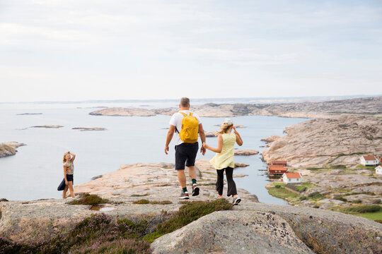 Family walking on rocks by coast