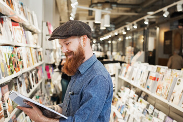 Bearded man reading magazine in store