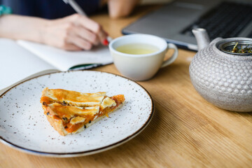 A woman makes a note in her notebook while sitting in a cafe.