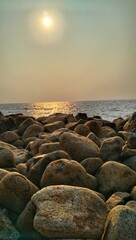 Rocky beach shore under the bright sun and rocks act as sea walls