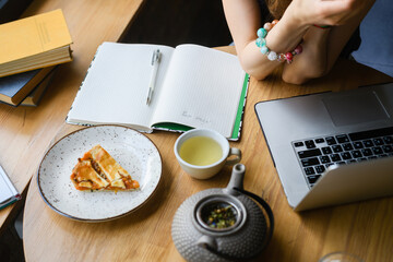 A woman makes a note in her notebook while sitting in a cafe.