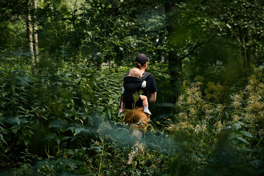 Woman walking through forest with daughter in baby carrier