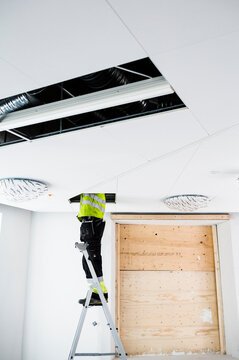 Construction worker on ladder working in ceiling