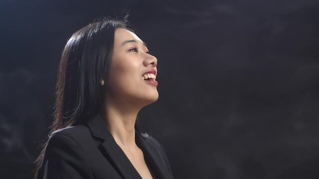 Close Up Of Asian Conductor Woman Holding A Baton And Showing Gesture Quickly In The Black Studio With Fog 
