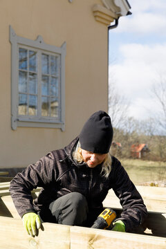 Mature Woman Drilling And Building Deck