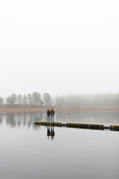 Young man and woman standing on pier at lake