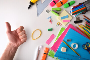 Assortment of colorful school supplies and hand with ok gesture