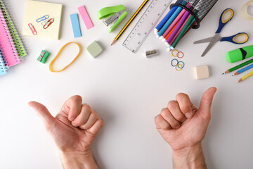 Assortment of school supplies and two hands with ok gesture