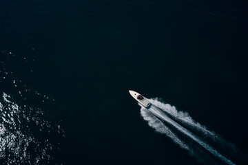 Speedy white boat movement on dark water aerial view. Expensive big super speed white boat with...