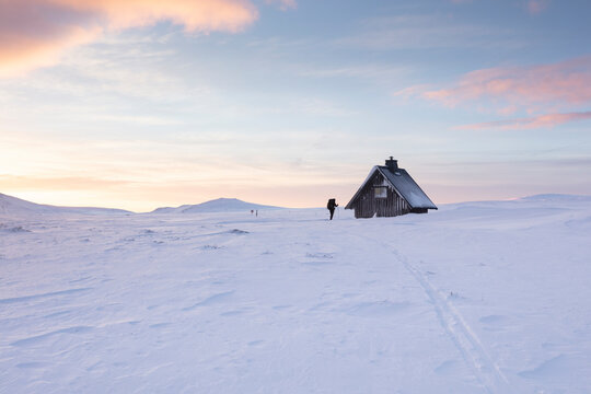 Woman cross-country skiing by log cabin in Rogen Nature Reserve Sweden