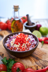 making salsa dip sauce - chopped garlic, tomatoes and onion in wooden bowl