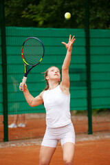 Young female tennis player serving.