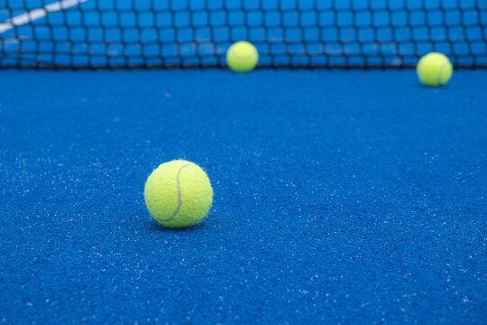 Selective focus. Paddle tennis balls on an open blue paddle tennis court. Racket sports concept
