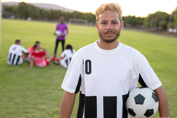 Naklejka premium Portrait of caucasian male player wearing white uniform with soccer ball standing at playground