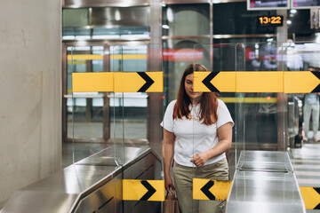 Woman traveler walking to automatic doors entrance at train station,Travel insurance concept. Redhead 30s Woman standing on urban city subway metro