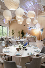 Wedding Decor. Festive table decorated with flowers on the center, candles, silverware and plates with silk napkins on dusty blue tablecloth