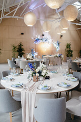 Wedding Decor. Festive table decorated with flowers on the center, candles, silverware and plates with silk napkins on dusty blue tablecloth