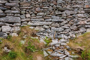 Natural ancient stone fence. Grunge stone wall granite background texture. Part of an old vintage castle stone barrier.