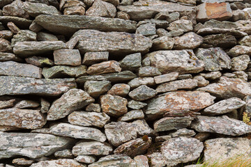 Natural ancient stone fence. Grunge stone wall granite background texture. Part of an old vintage castle stone barrier.