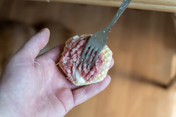 Cooking waffle crusts stuffed with minced meat. Step by step sequence. A man puts the raw stuffing...