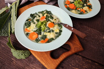 Healthy vegetable soup with kale. Above view table scene on a dark wood background