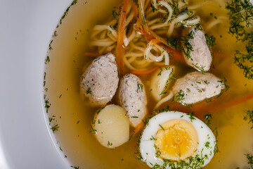 Soup with boiled eggs, noodles, meatballs, parsley