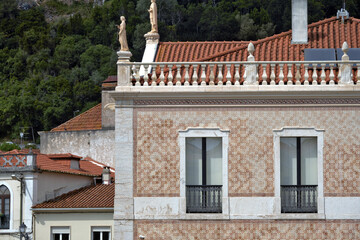 Traditional statue as a decoration on the roof of a classic house and facade covered with azulejos in Leiria, Portugal
