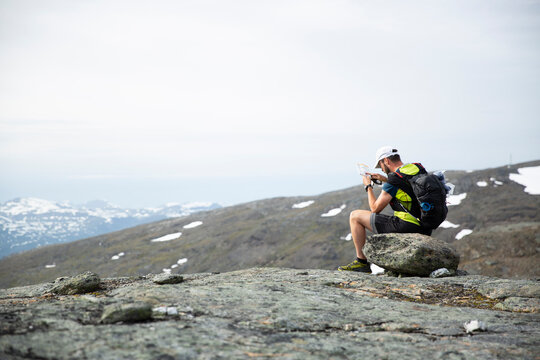 Mature man looking at map and compass on mountain