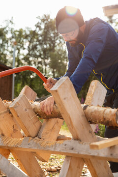 Man cutting firewood at sunset