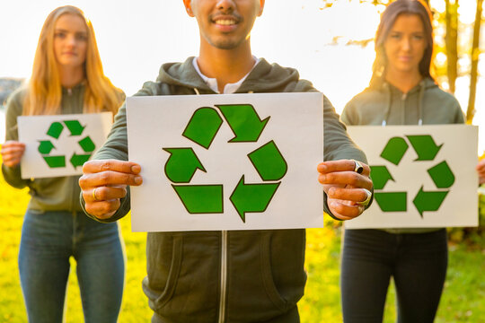 Team of environmental protection volunteers holding recycling symbol placards
