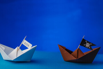 sos and pirate paper boat on blue water