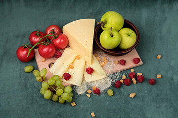 piece cheese with apples and tomatoes on a wooden board on a beautiful background