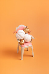 Creative autumn still life composition. Gold and white decorative pumpkins on a chair. Vertical format