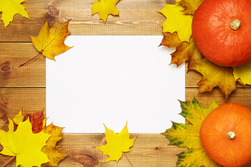 Blank paper with colorful autumn leaves and ripe pumpkins on wooden table top view.