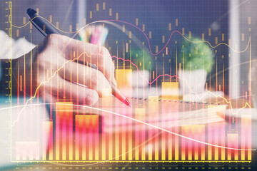 Financial forex charts displayed on woman's hand taking notes background. Concept of research. Double exposure