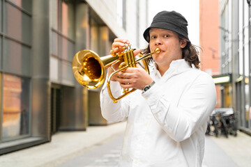 Young caucasian blond cheerful smiling man in white shirt and hat playing funky jazz on golden...