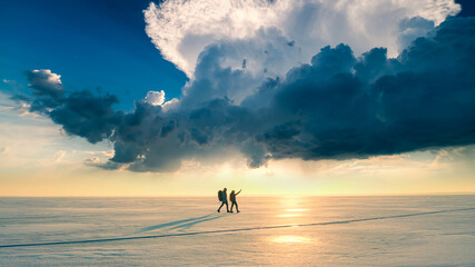 The two travelers going through the snow field on sunshine background