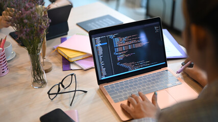 Over shoulder view of software developers programming on desktop computer in startup office - obrazy, fototapety, plakaty