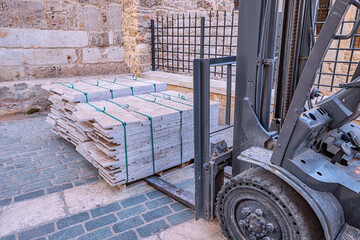 Forklift working with tiles cargo at construction site or warehouse. Industrial equipment and vehicle concept © EdNurg