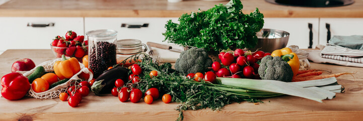banner background of fresh vegetables for salad on wooden table, peppers, tomatoes, cucumbers, broccoli and greens in cozy kitchen apartment