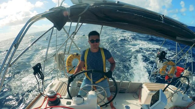 Front view of a steersman at the wheel of a sailboat